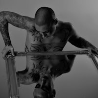 a man with tattoos standing in front of a mirror